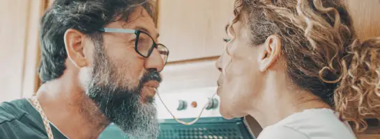 Een stel dat lachend met elkaar op de bank zit met de telefoon in de hand.