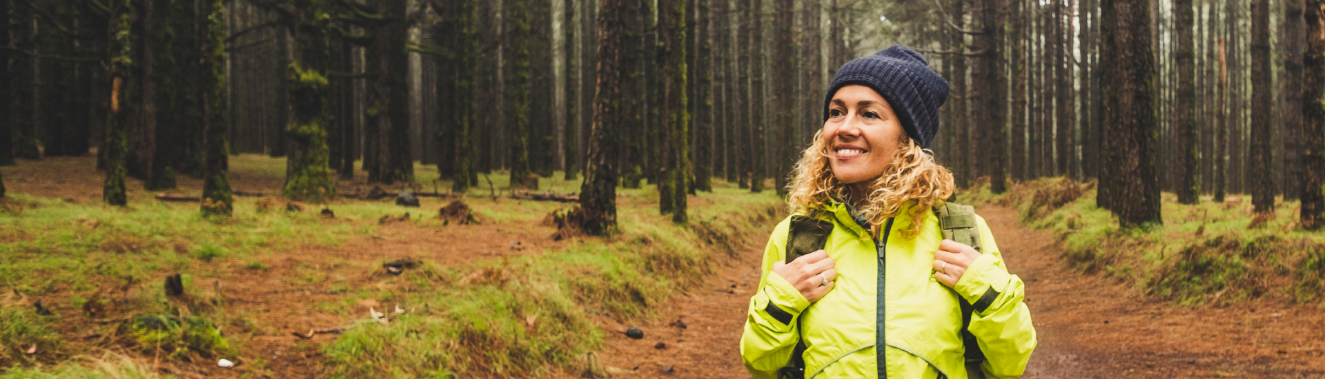 Een vrouw in sportieve winterkleding die lachend door een bos wandelt.