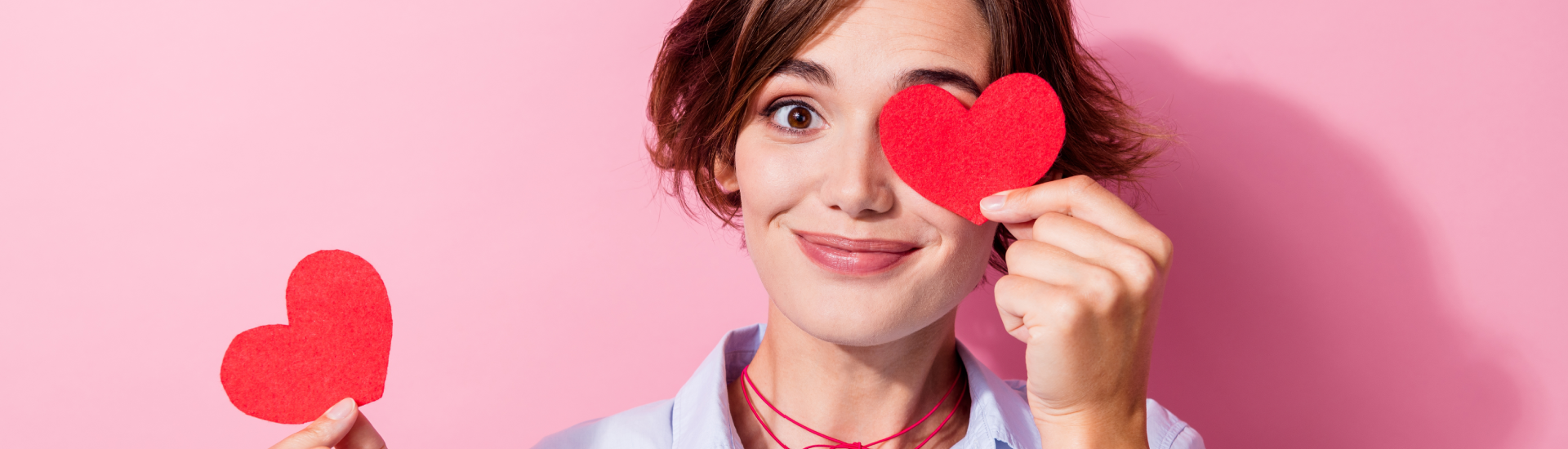 Een vrouw vriendelijk glimlachend met een hartje in beide handen voor Valentijn.