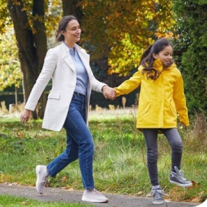 Moeder en dochter houden handen vast en lopen samen vrolijk door het bos.