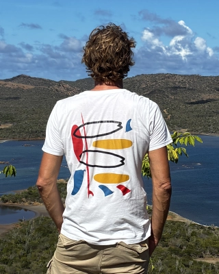 Model met een wit SWAKiKO T-shirt met kleurrijk surf design kijkt uit over het Goto meer op Bonaire