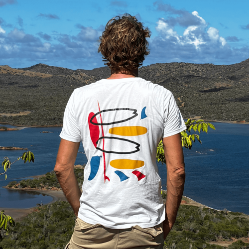 Model met een wit SWAKiKO T-shirt met kleurrijk surf design kijkt uit over het Goto meer op Bonaire 