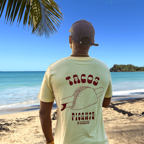 Model kijkt uit over de Caribische zee met een geel T-shirt met rugprint van een surfboard in een Mexicaanse taco