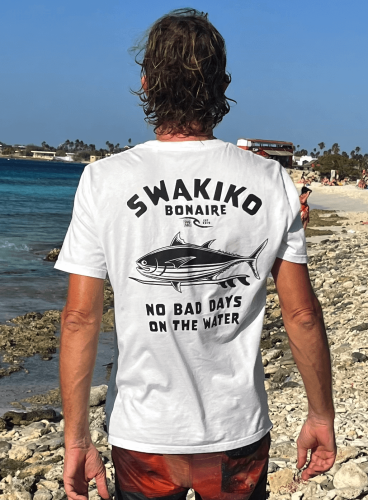 Model draagt een wit Bonaire T-shirt met tonijn op een surfboard en de tekst: No bad days on the water!