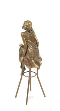 Een bronzen beeld van een topless dame op barkruk