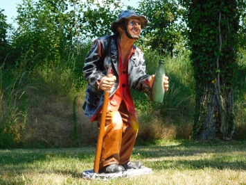 Große Statue eines alten Mannes mit einer Flasche Schnaps