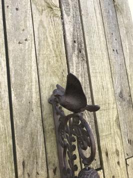 Een sierlijke deurbel met een vogel erop, gemaakt van gietijzer