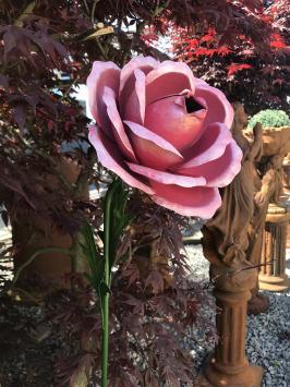 Een kunstwerkje, grote roze roos gemaakt van metaal, op steel