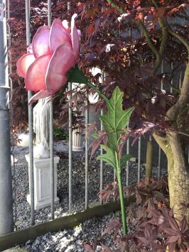 Ein Kunstwerk, große rosa Rose aus Metall, auf Stiel