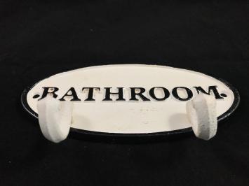 Een kapstok met 2 haken, bord met opschrift: 'BATHROOM' als achtergrond, gietijzer