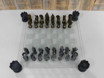 Ein Schachspiel mit dem Thema: 'Ritter-Drachen', schöne Schachfiguren als mittelalterliche Ritter auf einem Glasschachbrett mit Türmen.