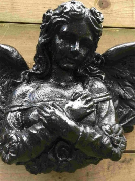 Detail van zwarte gietijzeren wandengel met sierlijke vleugels